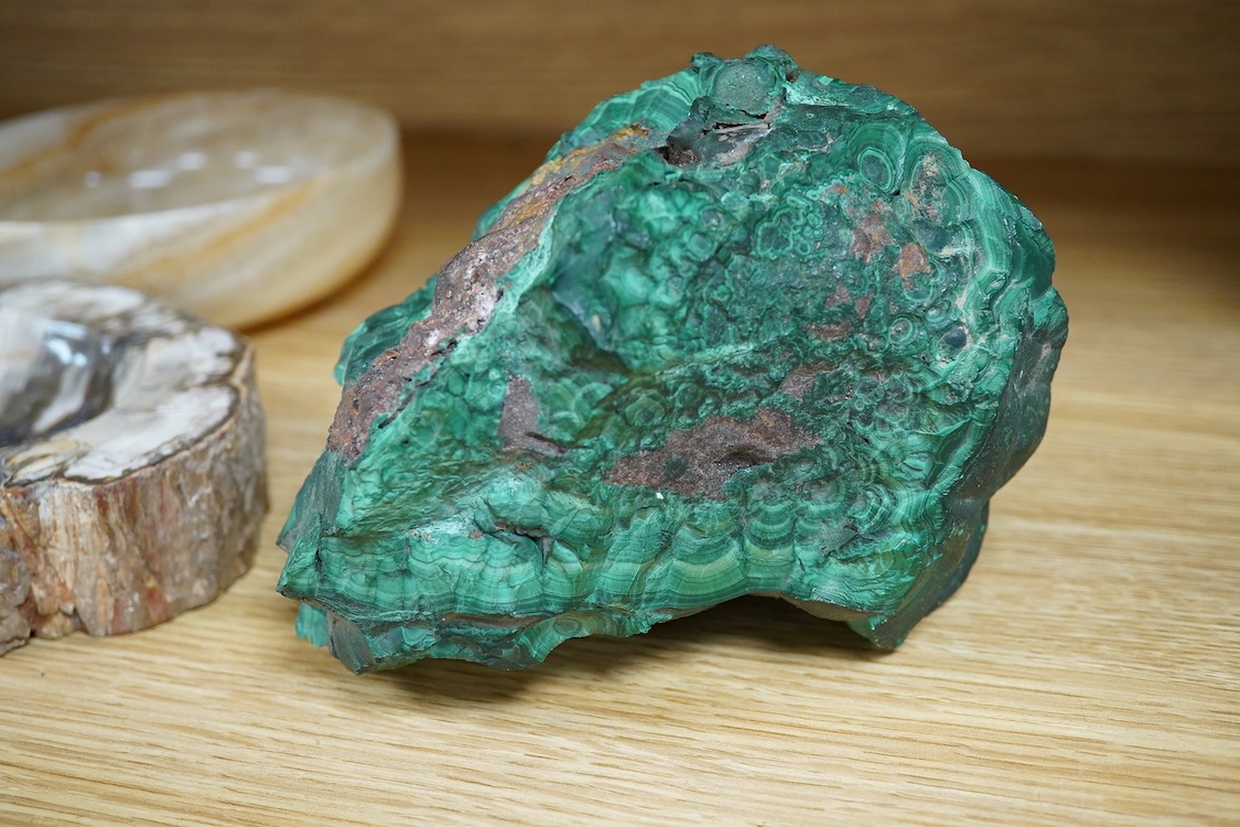 Two petrified wood ashtrays, a malachite rock, three onyx bowls, one with cover, and one other item, larger ashtray 17.5cm wide